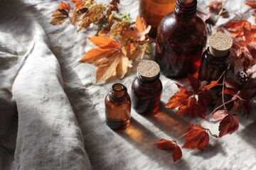 Autumn Leaves and Amber Bottles on Rustic Linen for Seasonal Aesthetic.