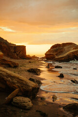 Secluded rocky cove at sunset with dramatic cliffs