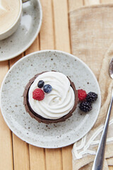 French dessert - cupcake with berries and cup of cappucino. Cozy breakfast at the terrace.