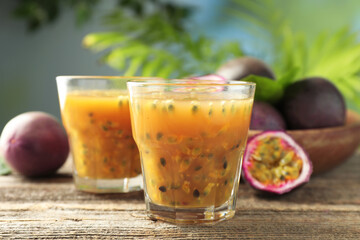 Tasty passion fruit drink and fresh fruits on wooden table, closeup