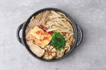 Tasty ramen with enoki and king oyster (eryngii) mushrooms on light grey table, top view