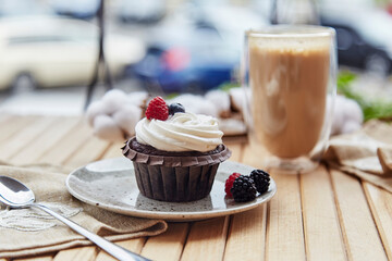 French gluten and sugar free raspberry and blueberry cupcake and cup of latte. Cozy autumn breakfast at the terrace.
