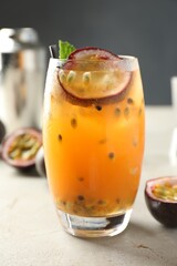 Tasty passion fruit drink in glass on gray table, closeup