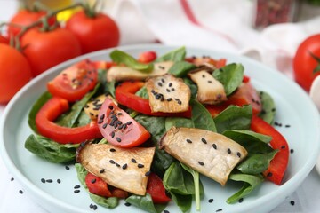 Tasty salad with eryngium mushrooms, vegetables, spinach and sesame on table, closeup