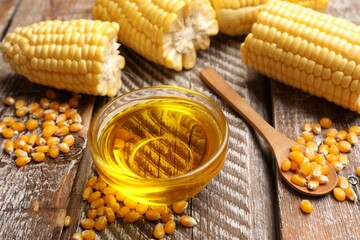 Corn oil, kernels and cobs on wooden table, closeup