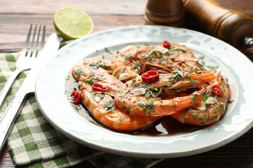 Tasty grilled shrimps with spices, sauce and cutlery on wooden table, closeup. Delicious seafood dish