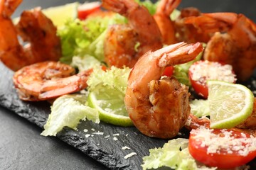 Tasty grilled shrimps with salad on black table, closeup. Delicious seafood dish