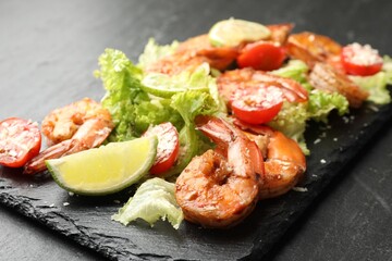 Tasty grilled shrimps with salad on black table, closeup. Delicious seafood dish
