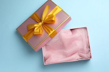 Opened gift box with beautiful lid on light blue background, top view