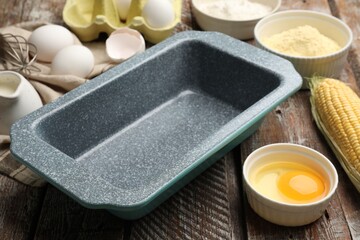 Making cornbread. Baking dish and different ingredients on wooden table, closeup