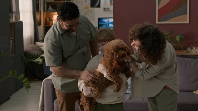 Pre-teen boy holding brown miniature poodle, happy parents petting dog after bringing it home for first time