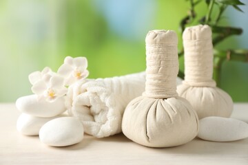 Beautiful spa composition with herbal bags on white wooden table against blurred background, closeup
