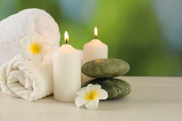 Beautiful spa composition with burning candles on white wooden table against blurred background, closeup