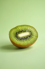 Vibrant half of kiwi fruit rests on green surface, juicy interior, tiny seeds. Minimal background, pastel colors food still life. Healthy, organic, fresh, bright fruit rich with vitamins.