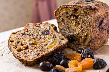 Healthy vegetarian gluten-free bread with cereals, prunes, dried apricots, nuts. Fresh baked bread on a board next to delicious cereals, grapes, prunes. Healthy food.