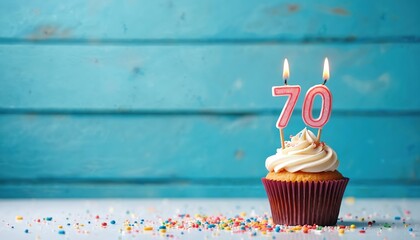 Festive cupcake with number 70 candles on blue wood background. Delicious cake celebrates seventy birthday anniversary with confetti sprinkles. Sweet dessert for happy celebration, event. Copy space.