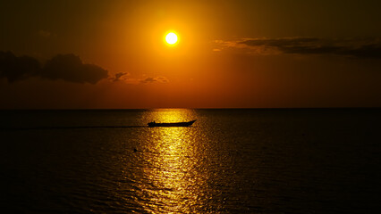 Obraz premium the sun begins to set and the silhouette of a fishing boat
