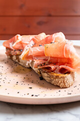 Prosciutto, bread, and spices on a plate, featuring italian cured meat appetizer