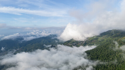 Aerial of Village in rain cloud cover tropical green mountain. Rainy season. Misty cover green forest. beautiful green village