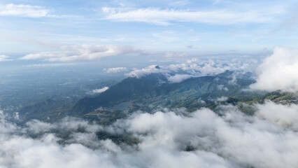 Aerial of Village in rain cloud cover tropical green mountain. Rainy season. Misty cover green forest. beautiful green village