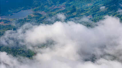 Obraz premium Aerial of Village in rain cloud cover tropical green mountain. Rainy season. Misty cover green forest. beautiful green village