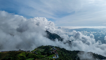 Aerial of Village in rain cloud cover tropical green mountain. Rainy season. Misty cover green forest. beautiful green village