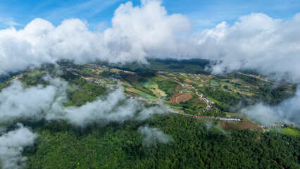 Aerial of Village in rain cloud cover tropical green mountain. Rainy season. Misty cover green forest. beautiful green village