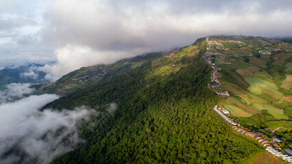 Aerial of Village in rain cloud cover tropical green mountain. Rainy season. Misty cover green...