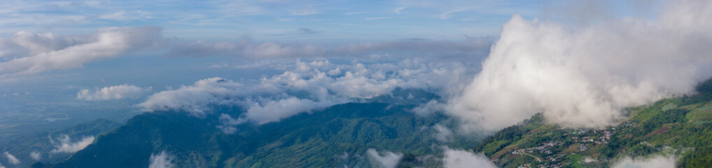 Aerial of Village in rain cloud cover tropical green mountain. Rainy season. Misty cover green...
