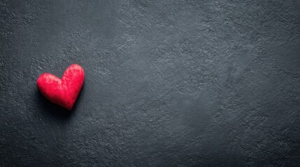 Obraz premium A vibrant red heart stands out against a dark grey textured background,
