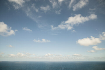 Fototapeta premium Blue sky with surreal clouds scattered over the sea