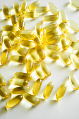 Heap of golden omega 3 capsules close-up on white background with bright light