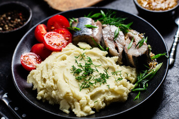 Herring with mashed potatoes tomatoes and mustard on a plate