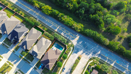 Median street leads to new two-story homes with sloped roofs, front garages, and adjacent greenbelt...