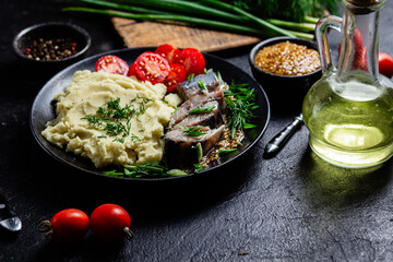 Herring with mashed potatoes tomatoes and mustard on a plate