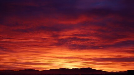 Fototapeta premium Stunning sunset with vibrant colors, deep purples blending into rich oranges and reds over dark mountains,