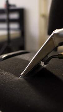 Cleanliness and dry-cleaning concept. Dry cleaning worker removing dirt with vacuum machine from soft armchair