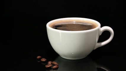White coffee cup with hot black coffee and roasted beans on black background