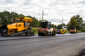Road construction with heavy rollers and paving machine on asphalt surface