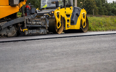 Close-up of yellow asphalt paving machine working on fresh road surface