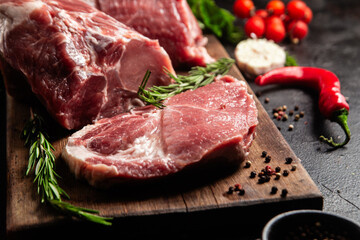 Raw Pork Cuts with Herbs and Spices on a Wooden Board