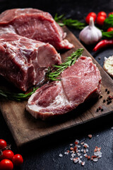 Raw Pork Cuts with Herbs and Spices on a Wooden Board