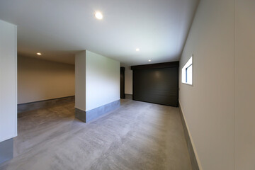 清潔感のある白い壁とコンクリート床を備えたシャッター付きガレージの室内空間