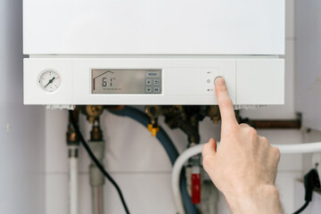 Repairman adjusting settings on gas boiler for optimal home heating