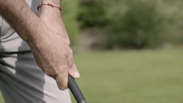 Golfer&rsquo;s hand gripping club in detail