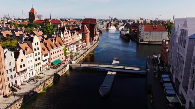 Drone footage shows Gdansk Old Town riverfront at sunrise with bridge view