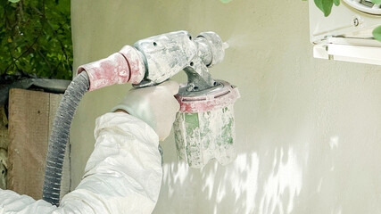 A Caucasian male in protective gear spray-paints a wall, evoking shades of Yom HaAliyah creativity and Arbor Day rejuvenation