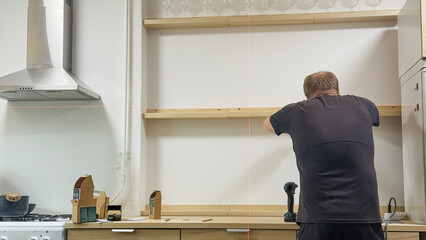 DIY artistry unfolds with a handy installation of floating shelves, as a Caucasian male embraces...