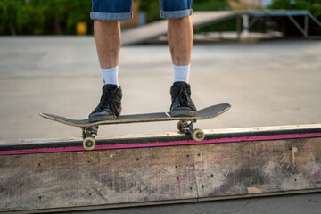 A skater is maintaining balance on a rail at a skate park during the late afternoon, showcasing skill and control while surrounded by a vibrant setting.