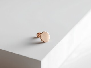 Fototapeta premium Rose gold earring on matte white surface with angled studio lighting